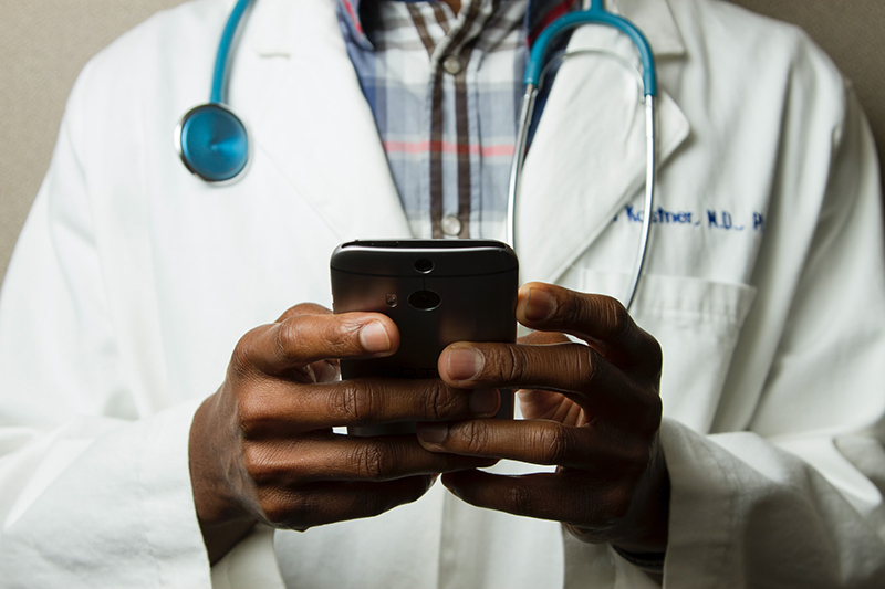 A doctor using his phone to sign up for suma.